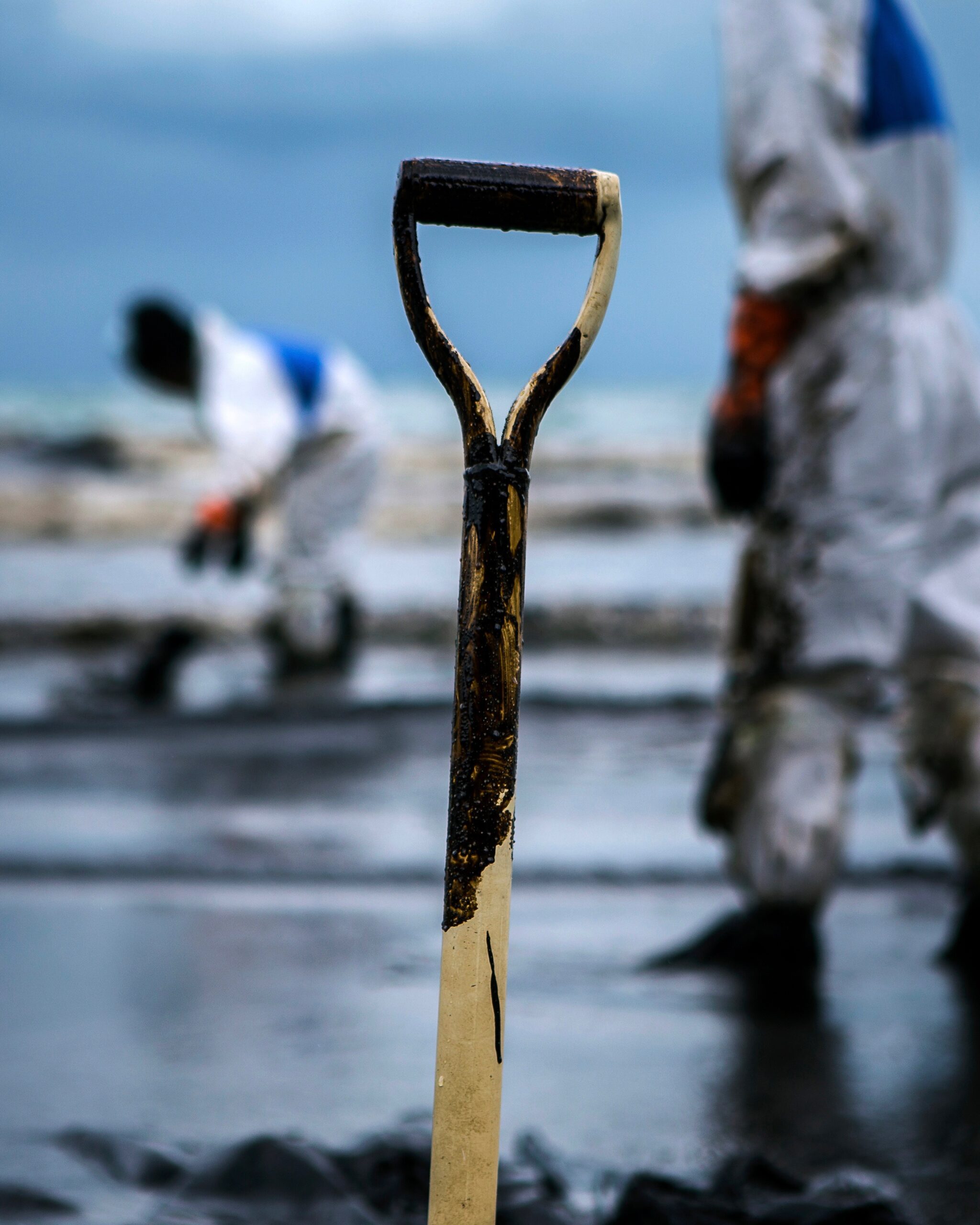 Workers remove crude oil from a beach