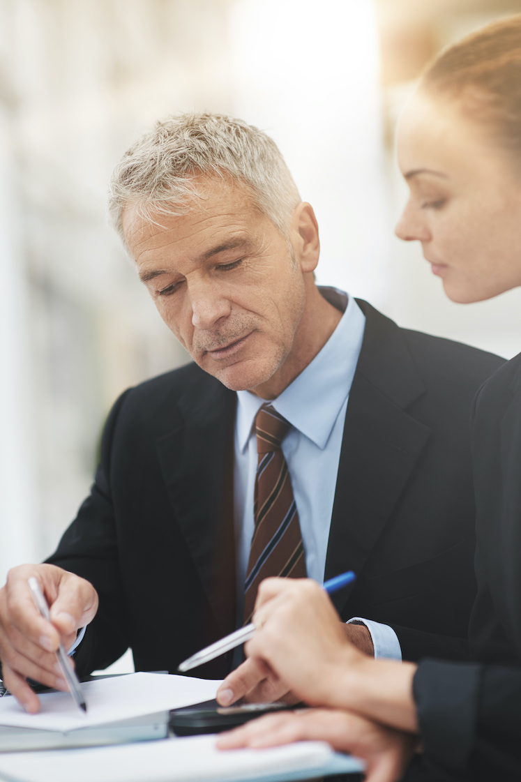 Shot of a two businesspeople discussing paperwork while sitting in an office