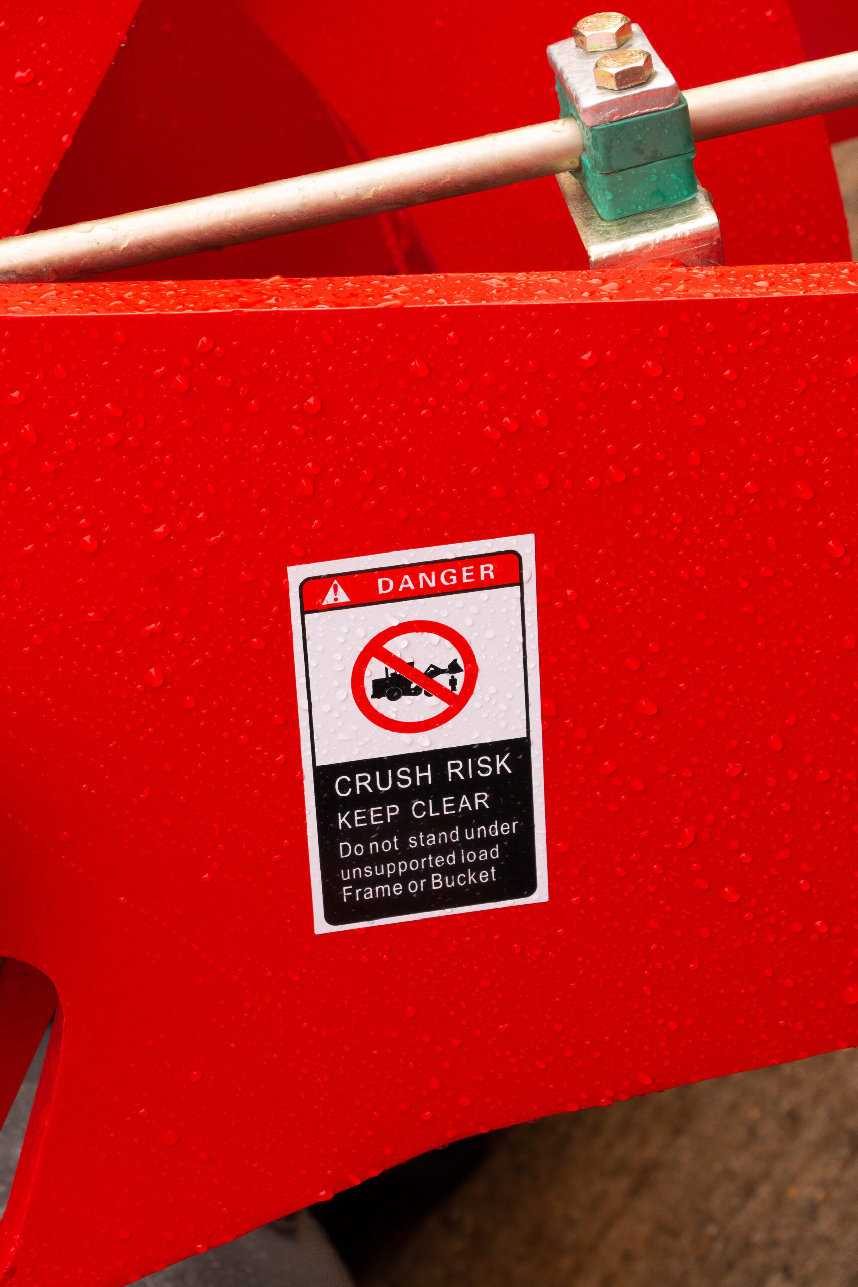 Danger warning sign of Crush Risk with symbol and Keep clear of frame or bucket on red forklift and tractor. Norfolk, UK - October 4th 2020