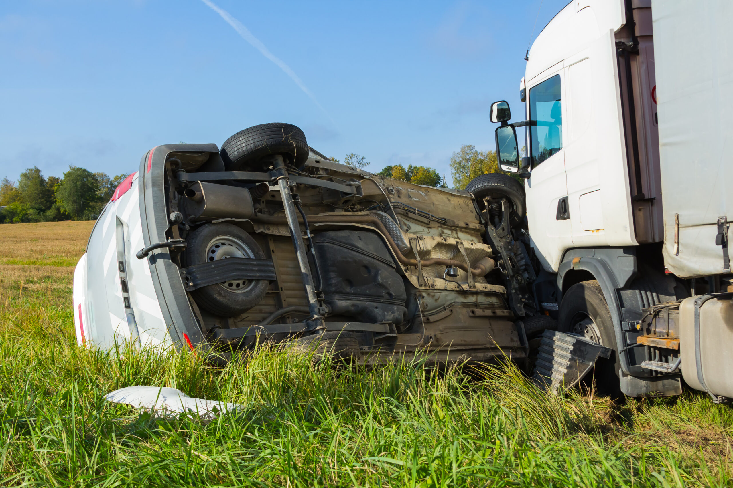 Car accident in the grass. the car is flipped after a collision with a heavy truck