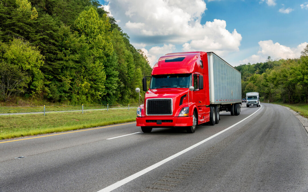 Horizontal shot of a red semi truck going down an interstate highway.