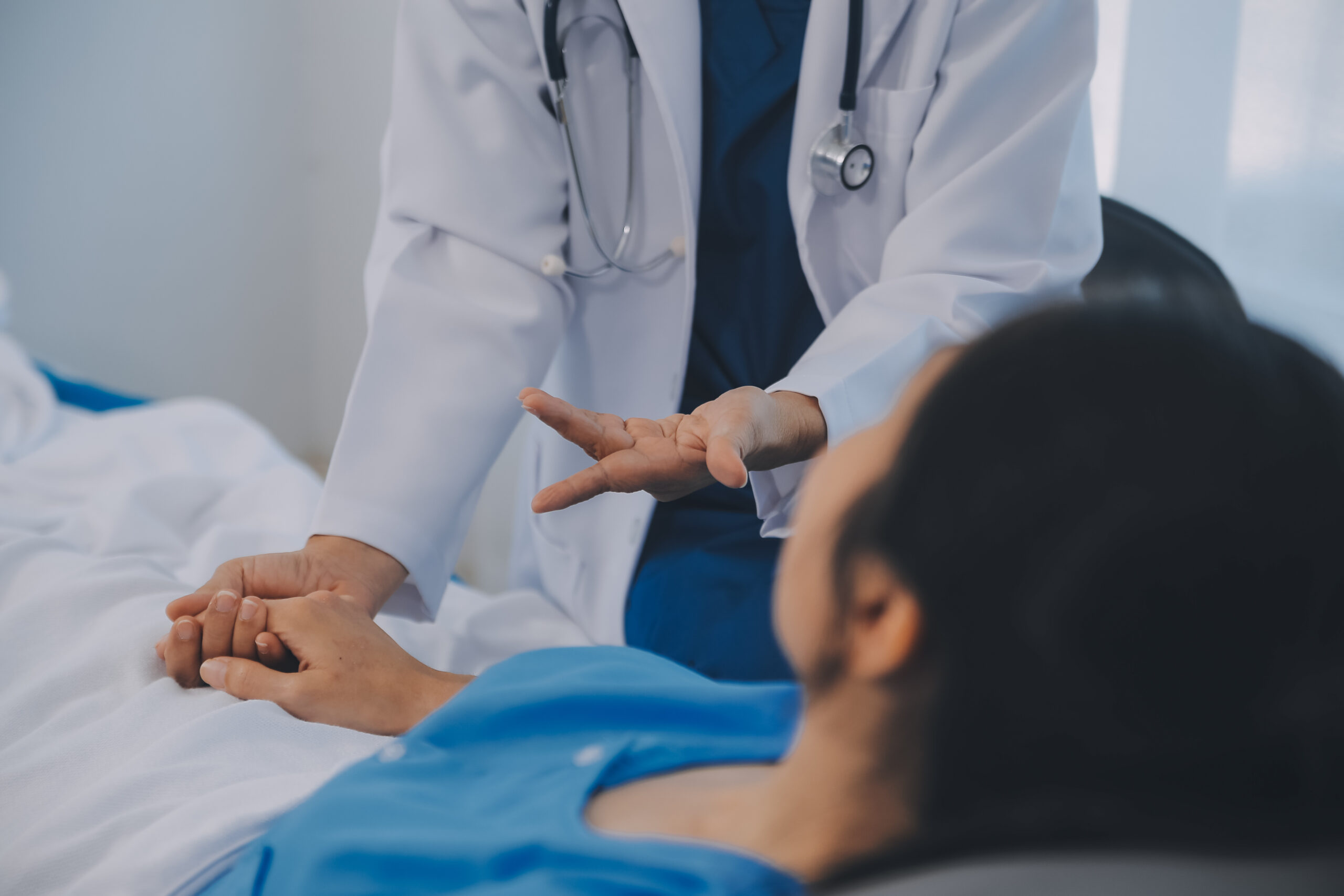 A doctor consoling a patient in a hospital bed