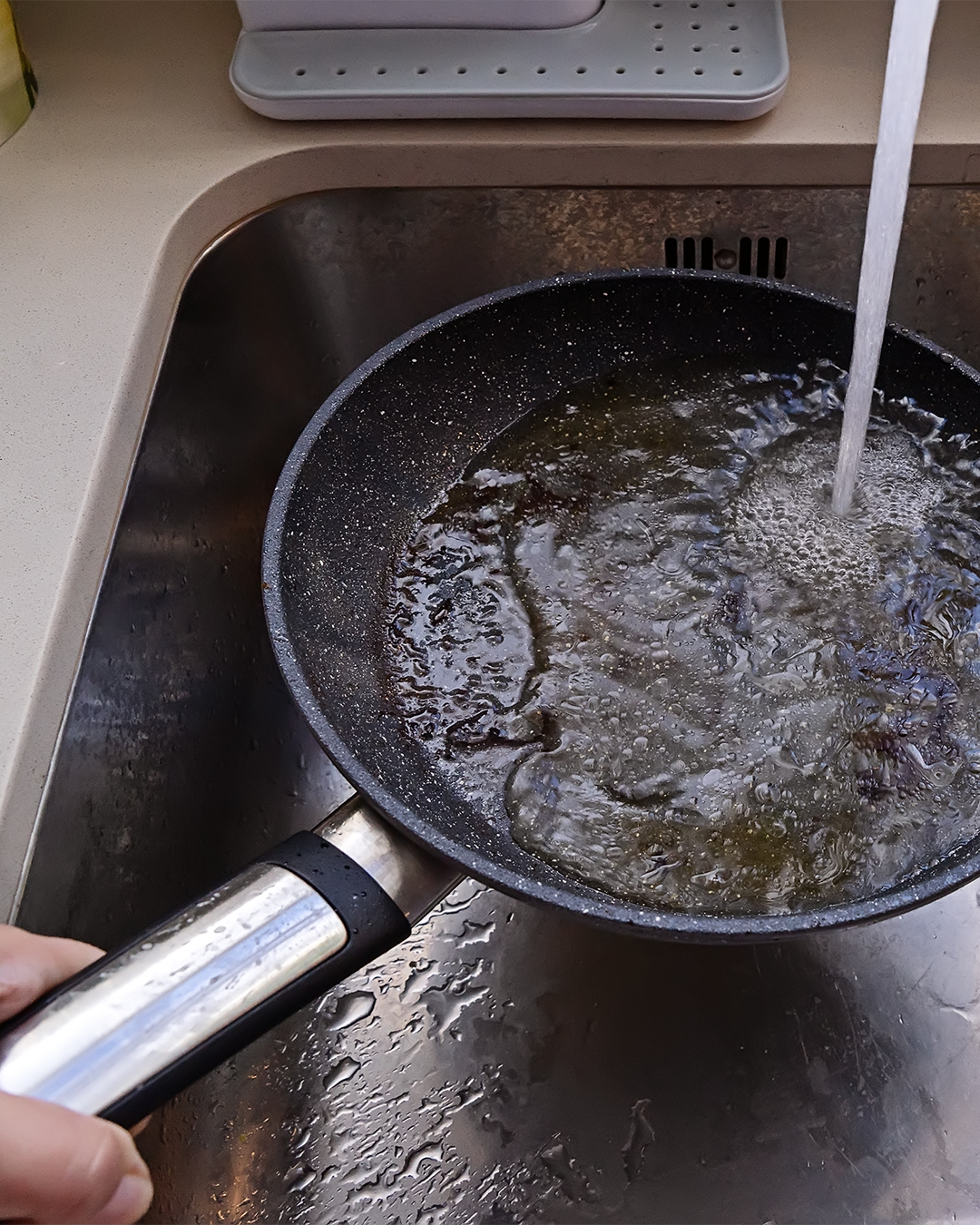 A cooking pan behind held in a sick while water fills it