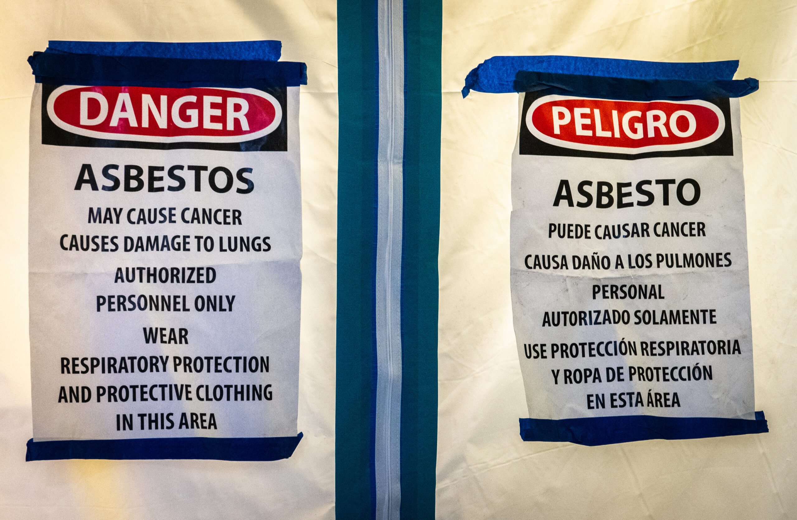 Warning signs for Asbestos. Sign reads: Danger. Asbestos. May Cause Cancer. Causes Damage to Lungs. Authorized Personnel Only. Wear Respiratory Protection And Protective Clothing In This Area.