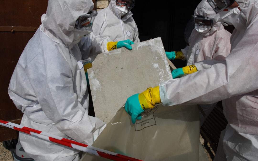 Workers in hazmat suits removing materials that contain asbestos fibers