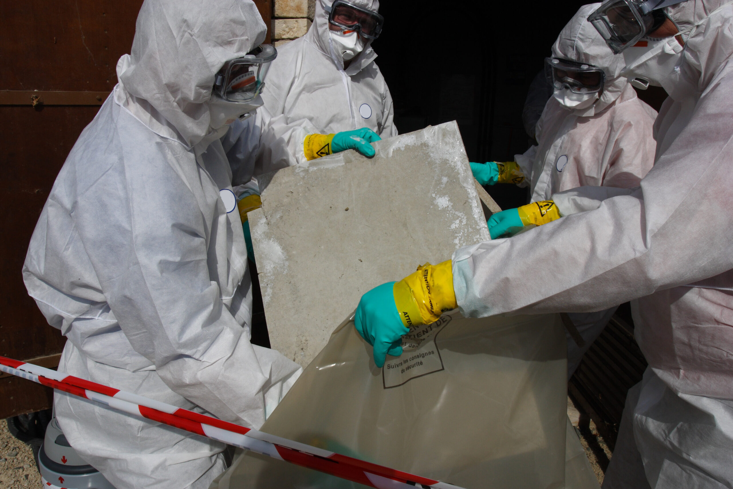 Workers in hazmat suits removing materials that contain asbestos fibers