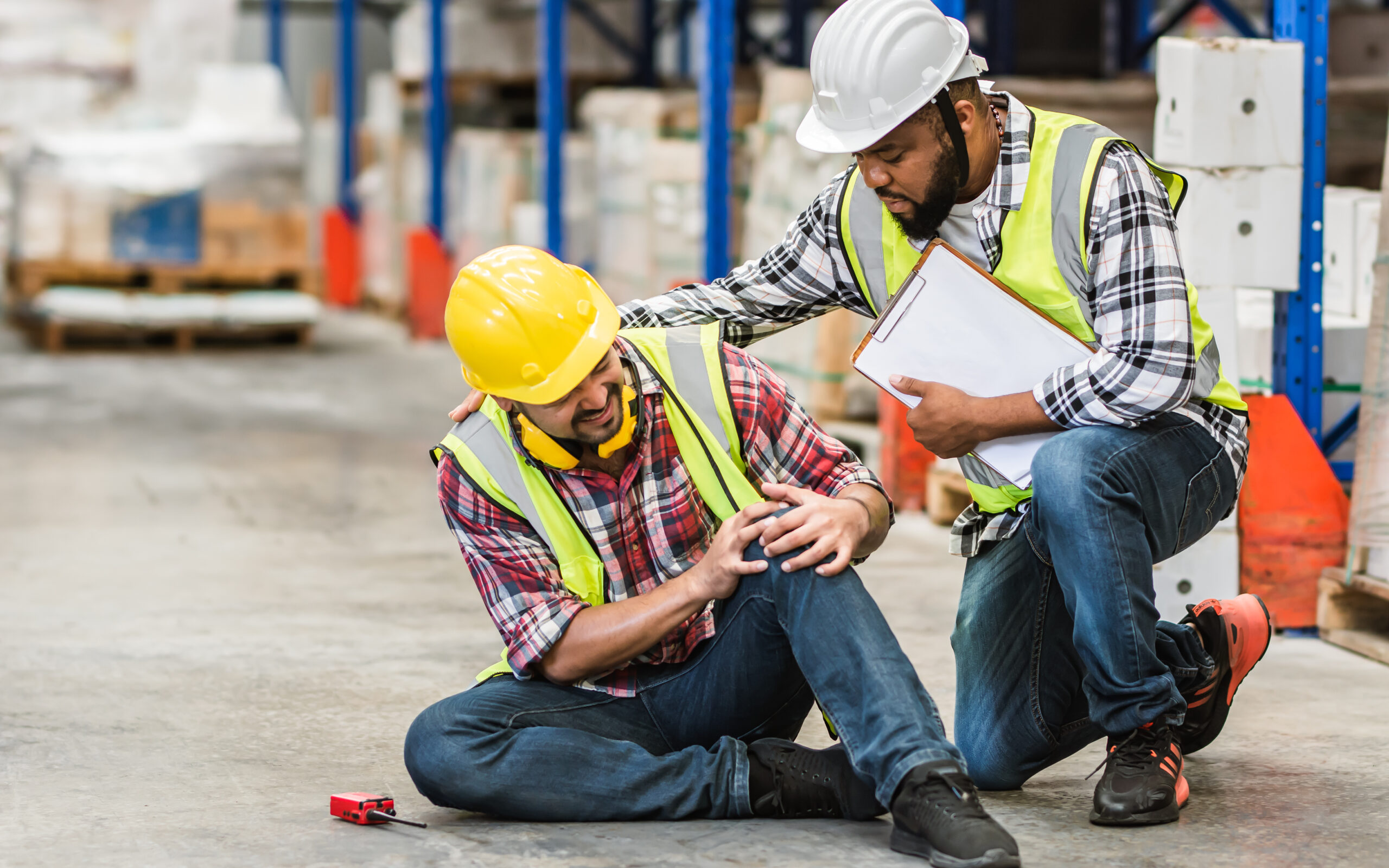 industrial or construction workers wearing hard hats, one worker appears to be injured