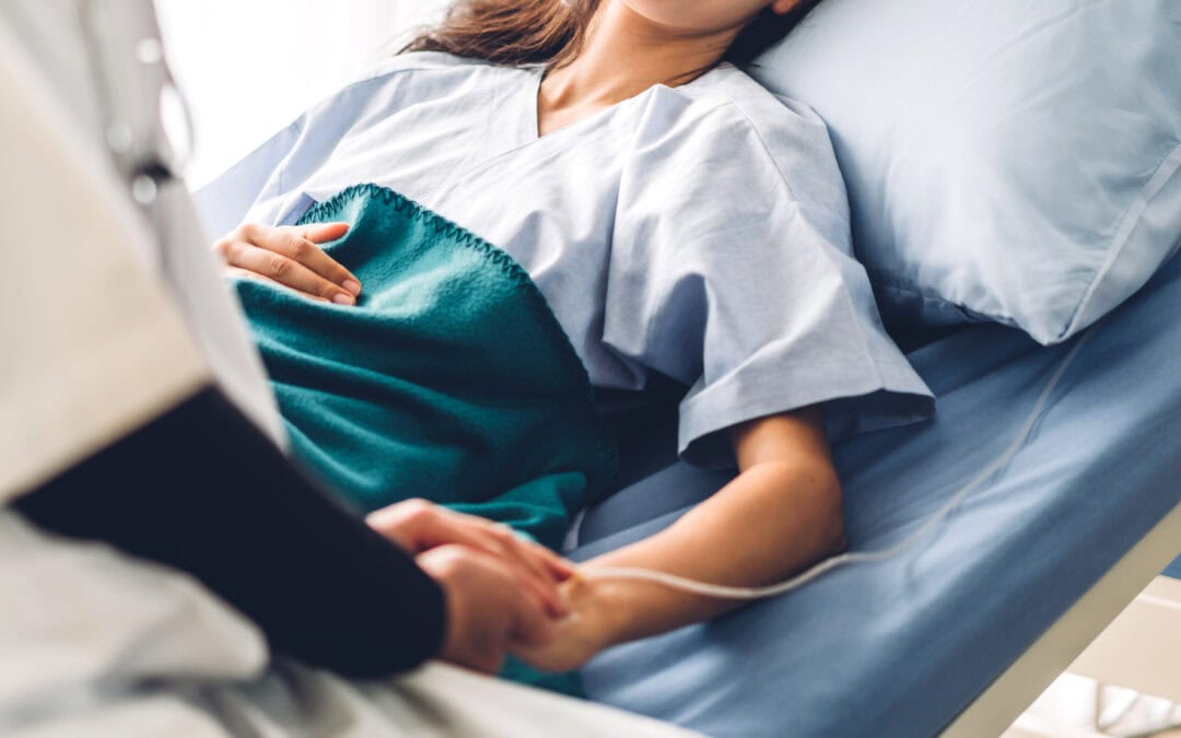 Female patient in hospital bed talking to doctor at bedside.