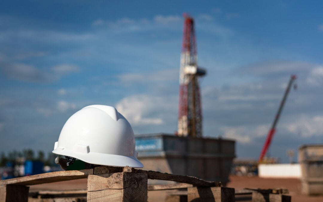 An oilfield worker safety hardhat or helmet is placed at onshore drilling rig site with blurred background