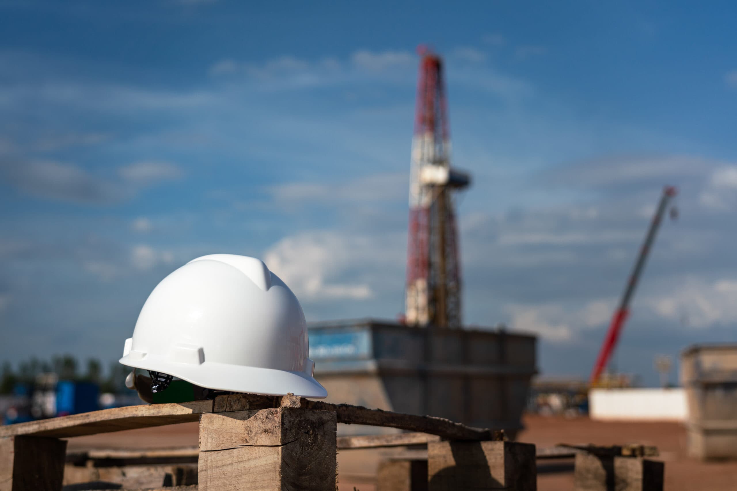 An oilfield worker safety hardhat or helmet is placed at onshore drilling rig site with blurred background