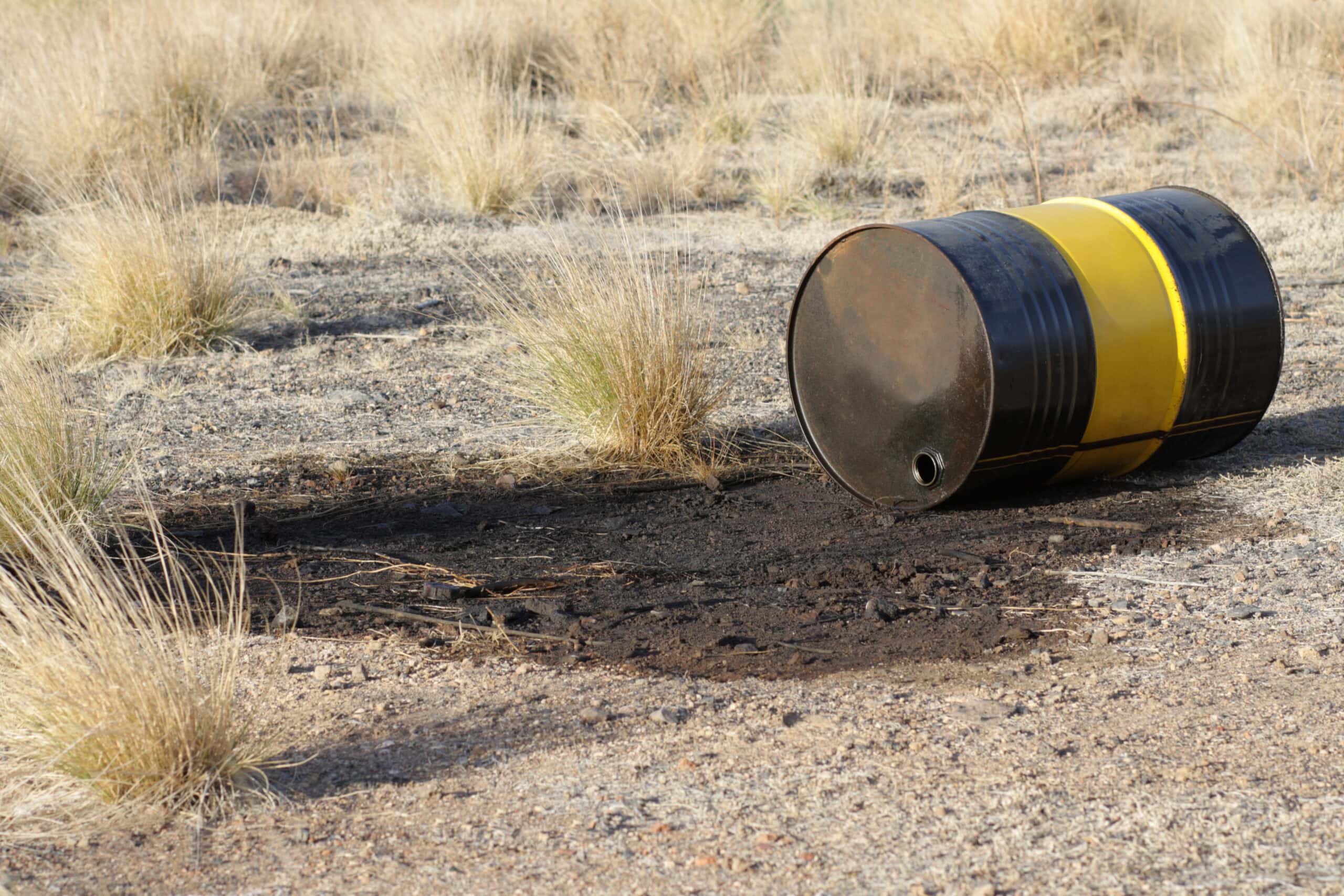 abandoned oil barrel in field leaking onto land