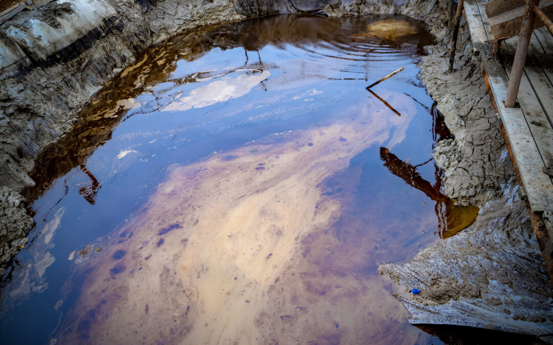 Oil and garbage pollution in the water. Selective focus with shallow depth of field. Iridescent colors abstract shapes on tar water surface