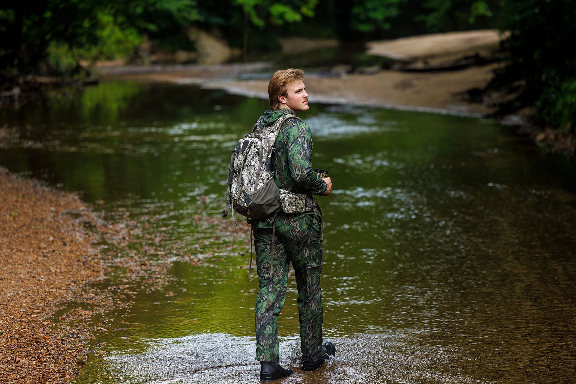 TCM NIL Campaign Landing Page_Image 2 Whit Weeks walking in a stream while hunting